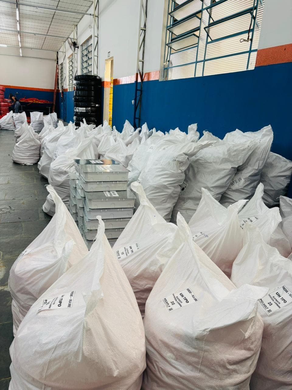 Galpão da Polvolt com dezenas de volumes lacrados e etiquetados por unidade habitacional, prontos para expedição
